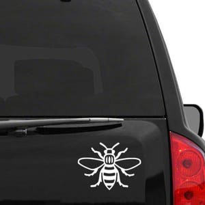 May include: A white bee silhouette sticker on the back window of a black car. The bee is a stylized design with wings and a body.