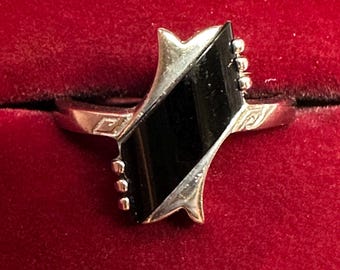 May include: A silver ring with a black onyx stone set in a geometric design.