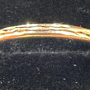 May include: A gold band ring with a textured design. The ring has a smooth, polished finish.