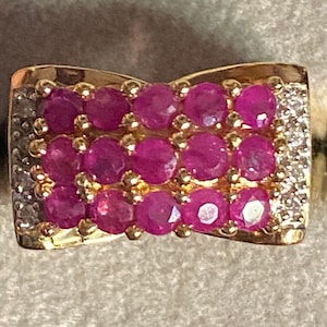 May include: A gold ring with a pink ruby stone setting. The ring is set with multiple ruby stones in a row.