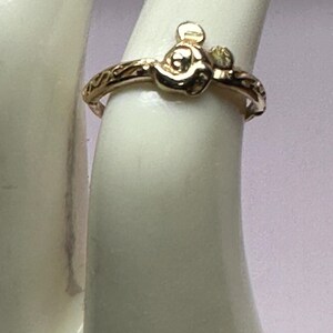 May include: Gold ring with a detailed design featuring a small Mickey Mouse head.