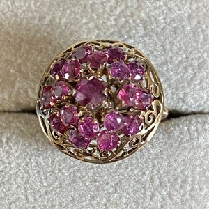 May include: A gold ring with a cluster of pink gemstones set in a delicate filigree design.