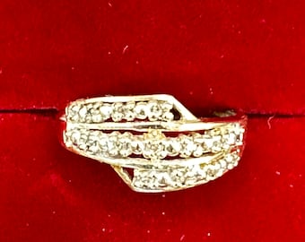 May include: A gold ring with a row of small diamonds on each band. The bands are intertwined and the ring has a simple design.
