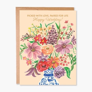 May include: A wedding greeting card with a watercolor floral bouquet in a blue and white vase. The card has the text "Picked with love, paired for life" and "Happy Wedding!" in gold lettering. The card is inside a brown envelope.