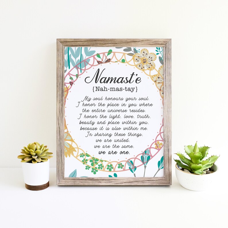 May include: A framed print with a floral design and the word "Namaste" in a decorative font. The print includes the definition of the word "Namaste" in English, which is "Nah-mas-tay". The text reads: "My soul honors your soul. I honor the place in you where the entire universe resides. I honor the light, love, truth, beauty and place within you, because it is also within me. In sharing these things, we are united. We are the same. We are one."