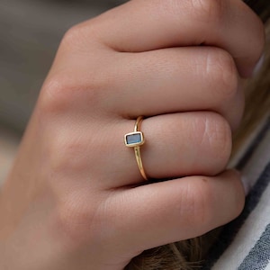 May include: A gold ring with a small, rectangular blue gemstone.