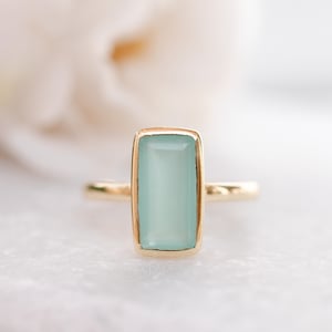 May include: A gold ring with a light blue rectangular gemstone.