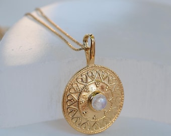 May include: A gold necklace with a round pendant featuring a moonstone and intricate heart-shaped designs.