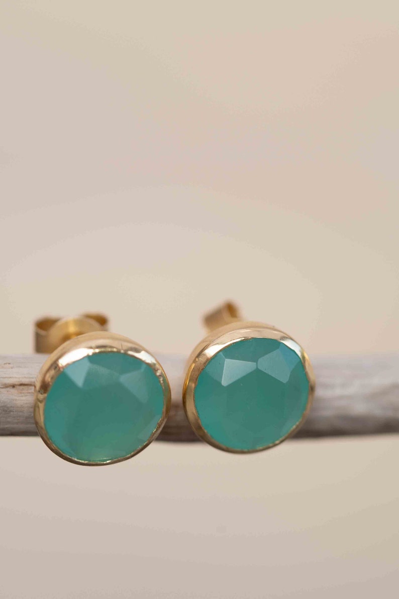 May include: A pair of gold stud earrings with teal gemstone accents.