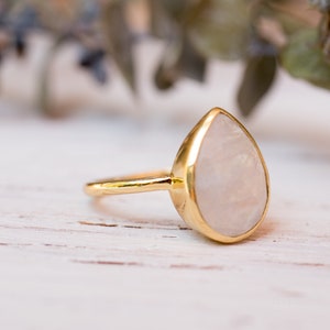 May include: A gold ring with a teardrop-shaped moonstone.
