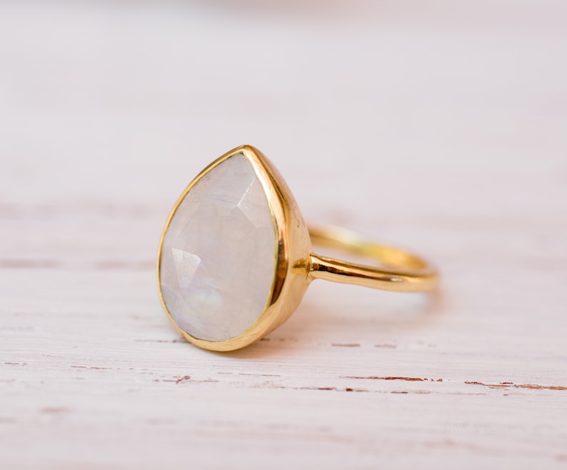 May include: A gold ring with a teardrop-shaped moonstone.