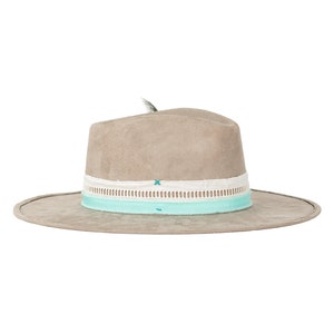 May include: A light gray suede fedora hat with a white and light blue ribbon band. The hat has a small feather accent on the top.