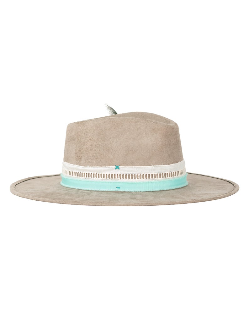 May include: A light gray suede fedora hat with a white and light blue ribbon band. The hat has a small feather accent on the top.