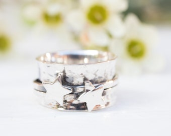 May include: A silver spinning ring with two star-shaped charms. The ring is textured and has a hammered finish.