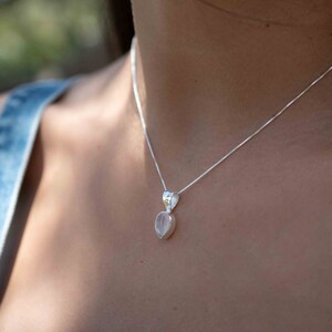 May include: A silver chain necklace with a delicate pendant featuring a light pink rose quartz gemstone.