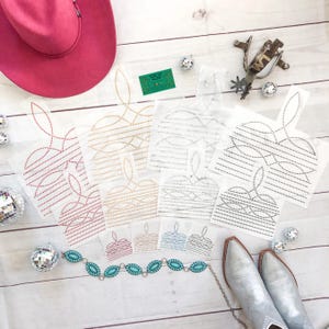 May include: A set of six rhinestone designs on clear sheets. The designs are in the shape of a crown with a curved top and a pointed bottom. The rhinestones are in various colors, including red, gold, silver, and black.