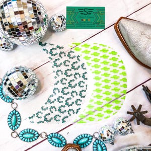 May include: Two half-moon shaped iron-on patches with different designs. One patch features a green cactus pattern on a white background. The other patch features a green and white geometric pattern on a white background. The text "Flying S Company" is visible in the top right corner of the image.
