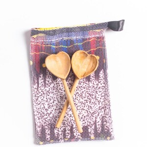 May include: Two wooden heart-shaped spoons in a mesh bag with a colorful patterned design.