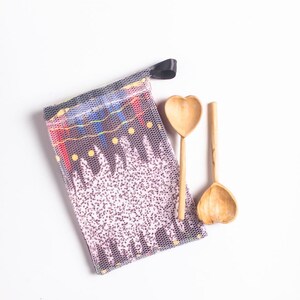 May include: Two wooden spoons with heart-shaped bowls, a black drawstring bag with a colorful patterned design, and a white background.