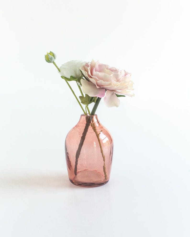May include: A pink glass vase with a textured surface holds a bouquet of pink and white flowers.