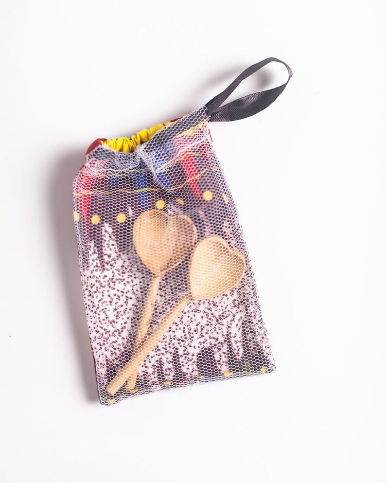 May include: A set of two wooden heart-shaped spoons in a mesh bag with a black drawstring. The bag has a colorful patterned design.