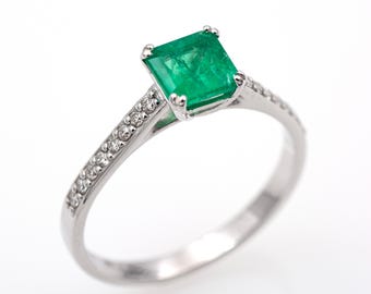 May include: A white gold ring with a square emerald gemstone and a band of small diamonds.