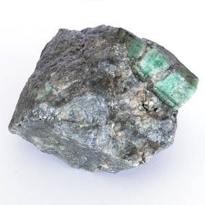 Large emerald green crystal with quartz and mica matrix weighing 916 grams.