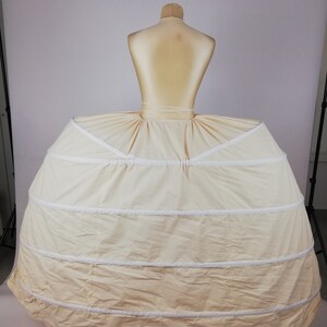 May include: A white petticoat with multiple layers and a ruffled edge. The petticoat is designed to create a full, voluminous skirt.