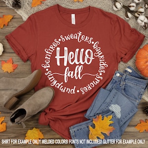 May include: A red t-shirt with a white circle design that says "Hello Fall" with the words "bonfires", "sweaters", "hayrides", "smores", and "pumpkin" around the circle.