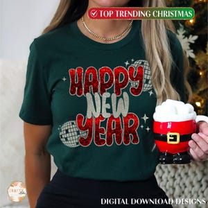 以下が含まれることがあります： 「Happy New Year」と赤いグリッターで書かれた緑色のTシャツと、銀色のグリッターで飾られたディスコボールのグラフィック。