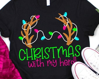 May include: Black t-shirt with a graphic of reindeer antlers with Christmas lights wrapped around them. The text "Christmas with my herd" is written below the antlers.