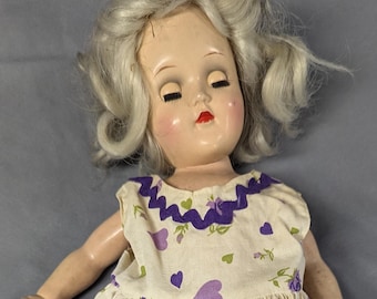 Boneca Ideal P90 dos anos 1950 com vestido floral roxo.