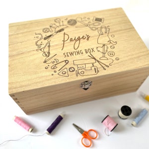 May include: A light wood sewing box with a hinged lid and a latch. The lid is engraved with a design of sewing tools and the text "Paige's Sewing Box".