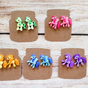 May include: Six pairs of colorful pony earrings. Each pair features a different color pony, including green, pink, yellow, blue, and purple.