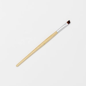 May include: A wooden handled angled brush with a silver ferrule and brown bristles.