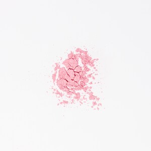 May include: A close-up of a pink powder blush makeup product on a white background.