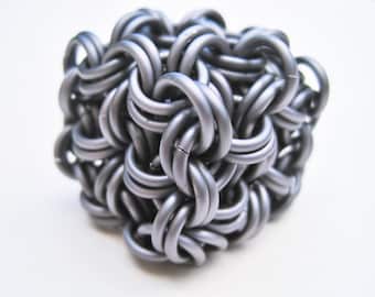 May include: A silver metal chainmail ball, also known as a  'Celtic Knot' or 'Chinese Knot', is a decorative object made of interwoven metal rings.
