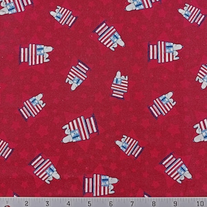 May include: Red fabric with a repeating pattern of white dogs sitting on top of a small house with an American flag. The house is red, white, and blue.