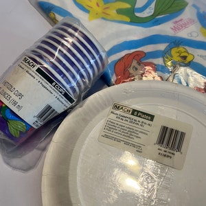 May include: A set of 8 purple and white paper cups and 8 white paper plates with a plastic coating. The plates are 22.8 cm in diameter. The packaging features a Disney Little Mermaid theme with images of Ariel and Flounder.