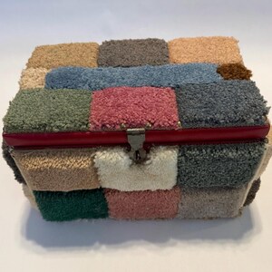 May include: A rectangular box with a patchwork design made from various colors of carpet squares. The box has a red trim and a metal clasp. Colors include beige, green, pink, blue, and gray.