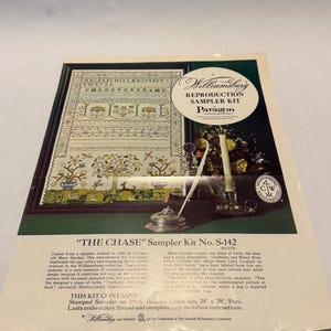 May include: A Williamsburg reproduction sampler kit by Paragon Needlecraft titled The Chase, kit number S-142. The packaging features a printed image of an embroidered sampler on 28 by 20 inch Belgian linen, alongside a candle and glass decanter.