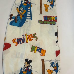 Puede incluir: S&aacute;bana bajera blanca con Mickey Mouse, Goofy y el Pato Donald en poses juguetonas. La s&aacute;bana tiene las palabras "Smiles", "Play" y "Hang Around" en letras coloridas. La s&aacute;bana est&aacute; dise&ntilde;ada con un tema de dibujos animados.