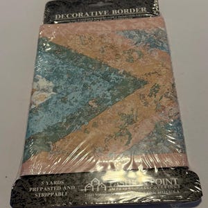 Pode incluir: Um rolo de borda decorativa para papel de parede em embalagem plástica. A borda apresenta um padrão de formas geométricas azuis, pêssego e bege. A embalagem diz "DECORATIVE BORDER" e "5 YARDS PREPASTED AND STRIPPABLE".