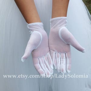 Puede incluir: Un par de guantes de malla blanca semitransparente con delicados detalles de encaje floral en la zona de la mu&ntilde;eca. Los guantes son ligeros y ligeramente transparentes, extendi&eacute;ndose hasta la mu&ntilde;eca con un dobladillo limpio. El texto www.etsy.com/shop/LadySolomia es visible.