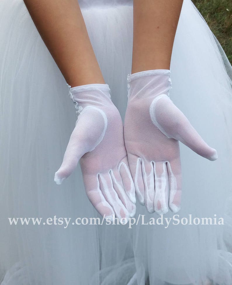 Puede incluir: Un par de guantes de malla blanca semitransparente con delicados detalles de encaje floral en la zona de la mu&ntilde;eca. Los guantes son ligeros y ligeramente transparentes, extendi&eacute;ndose hasta la mu&ntilde;eca con un dobladillo limpio. El texto www.etsy.com/shop/LadySolomia es visible.