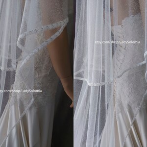 Puede incluir: Un velo de novia blanco con un acabado brillante sutil y un borde trenzado decorativo, combinado con un vestido largo con detalles de encaje aplicado, una espalda estilo cors&eacute; con cordones y una falda de sat&eacute;n suave. El texto dice etsy.com/shop/LadySolomia.