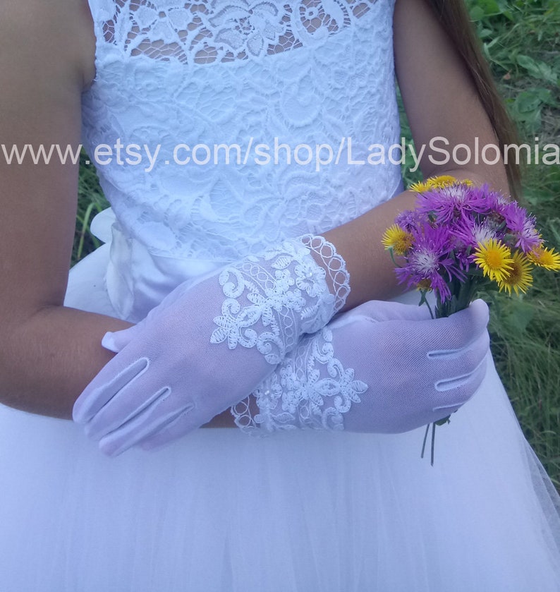 Puede incluir: Guantes blancos hasta la mu&ntilde;eca con intrincados bordados de encaje floral y bordes festoneados en los pu&ntilde;os. Los guantes se llevan con un vestido blanco con estampado de encaje y sostienen un peque&ntilde;o ramo de flores silvestres moradas y amarillas. El texto dice www.etsy.com/shop/LadySolomia.