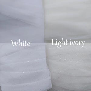 May include: A split-view display of sheer fabric swatches. The left side shows white tulle, with the top section plain and the bottom section featuring subtle glitter. The right side shows light ivory tulle, also with plain and glittered sections.