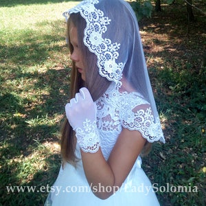 Puede incluir: Un velo de encaje blanco con bordados florales y bordes festoneados, combinado con guantes de encaje blanco a juego con intrincados patrones florales. El conjunto se lleva con un vestido blanco de cuerpo de encaje y falda lisa, con el texto www.etsy.com/shop/LadySolomia visible en la parte inferior de la imagen.