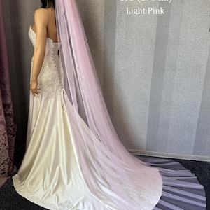 May include: A long, light pink tulle veil measuring 108 inches in length, draped over a strapless, floor-length ivory gown with lace detailing on the bodice and hem. The text 108" (270 cm) Light Pink is visible in the upper right corner.